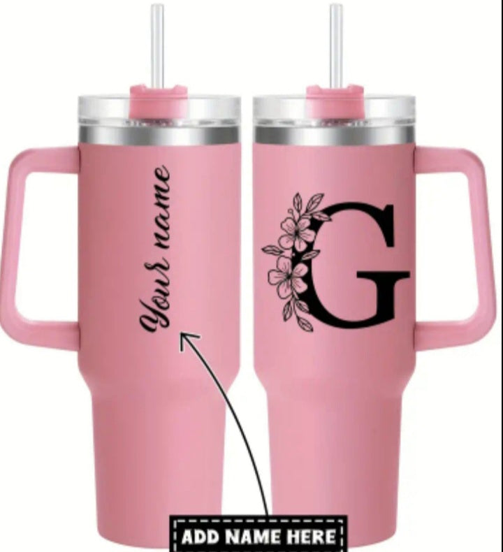Two pink tumblers with handles and straws, one personalized with 'Your name' and the other with a floral 'G'.