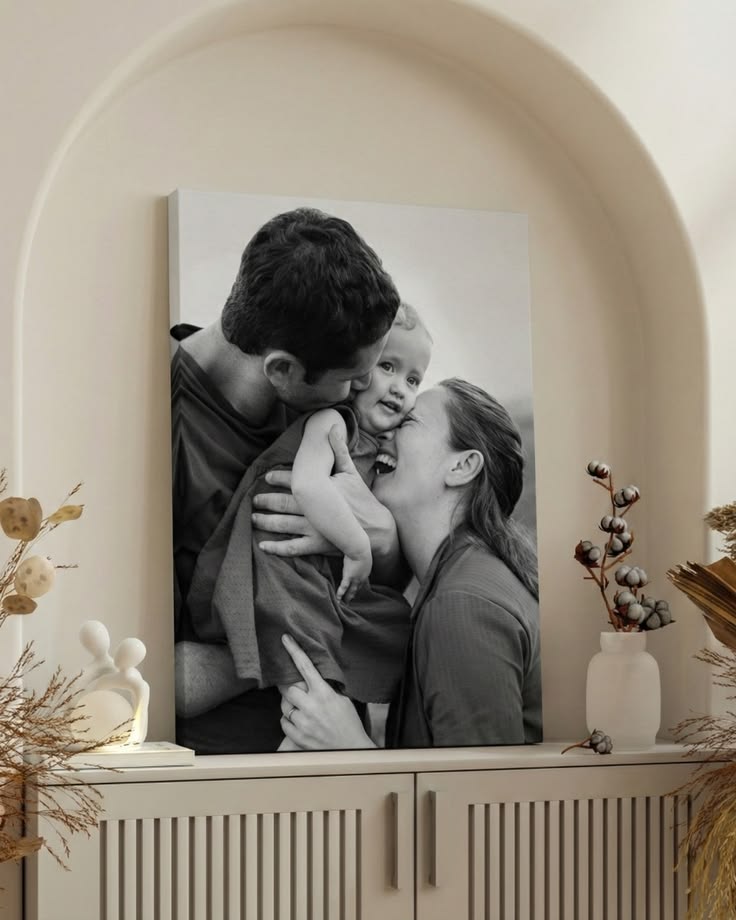 Black and white photo of a family hugging displayed on a wall with decorative elements.